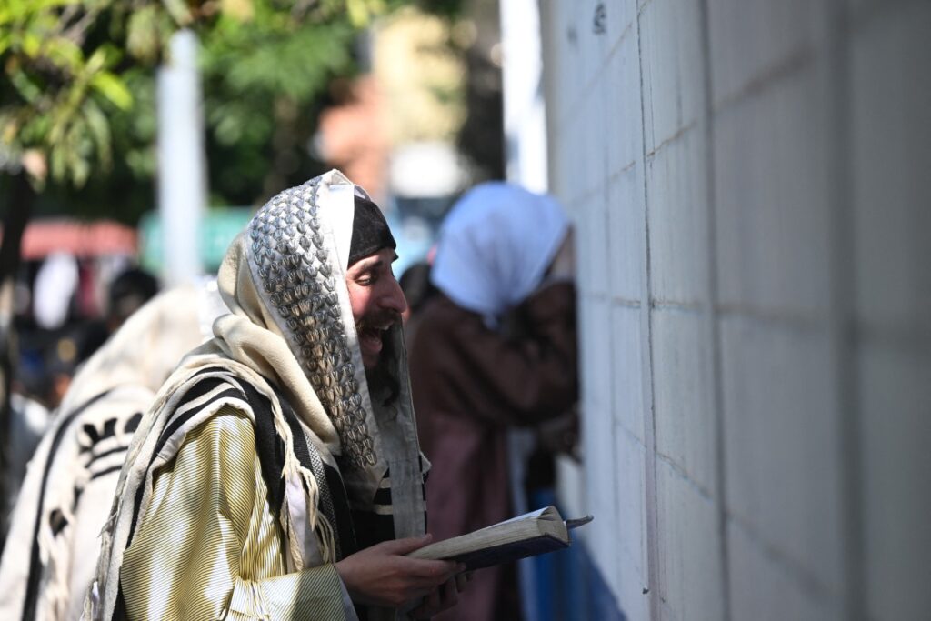 Miembros de la comunidad judía Lev Tahor oran frente a la escuela de educación especial Alida España de Arana donde permanecen los niños rescatados en la ciudad de Guatemala (Foto de Johan ORDÓÑEZ/AFP)