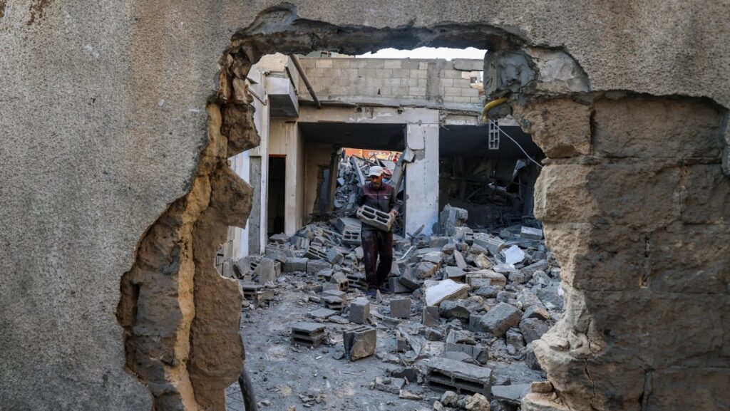 Un hombre transporta bloques de hormigón recuperados dentro de un edificio alcanzado por un ataque israelí en el campamento de refugiados palestinos de Bureij, en el centro de la Franja de Gaza, el 2 de mayo de 2025. (Foto de Eyad BABA / AFP)