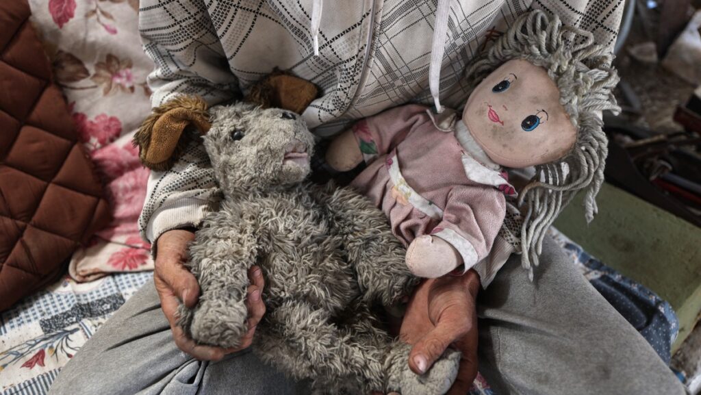 El padre palestino Wissam Wishah, quien perdió a tres de sus hijos, Said, Salma y Eline, en ataques israelíes cerca de su casa, recoge sus juguetes para colgarlos entre los escombros de su casa en el campo de refugiados de Al-Bureij, en el centro de la Franja de Gaza, el 1 de mayo de 2025. (Foto de Eyad BABA / AFP)
