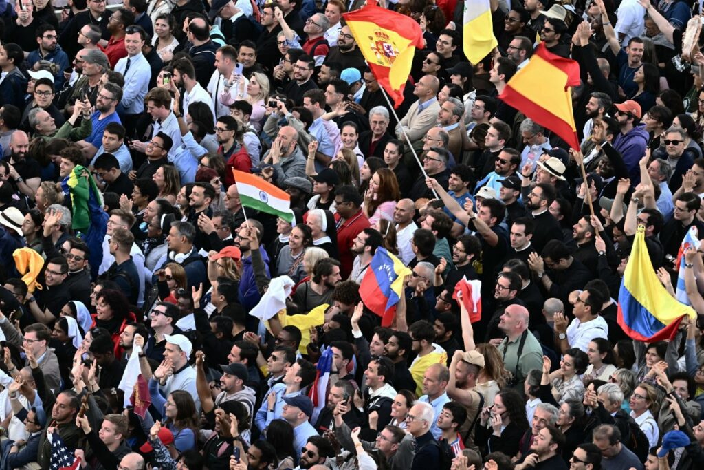 La gente ondea banderas antes de la primera aparición del nuevo Papa, después de que los cardenales concluyeran el cónclave, en el Vaticano, el 8 de mayo de 2025. (Foto de Filippo MONTEFORTE / AFP)
