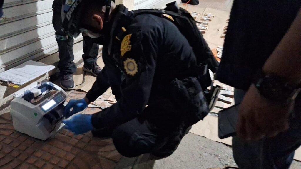 Agentes antinarcóticos cuentan el dinero localizado en un compartimiento oculto del camión. (Foto: PNC)