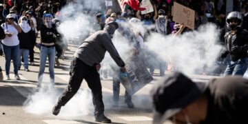 Un manifestante lanza una bomba de gas lacrimógeno contra las fuerzas del orden durante los enfrentamientos que estallaron después de que las autoridades declararan ilegal una reunión durante la protesta "Sin Reyes" contra la administración Trump en Los Ángeles el 14 de junio de 2025, el mismo día del desfile militar de Trump en Washington, D.C. (Foto de ETIENNE LAURENT / AFP)